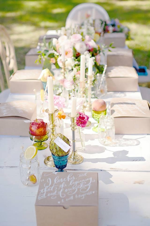 Bright florals, colorful glassware, and glamorous candles create a beautiful tablescape for an outdoor wedding.