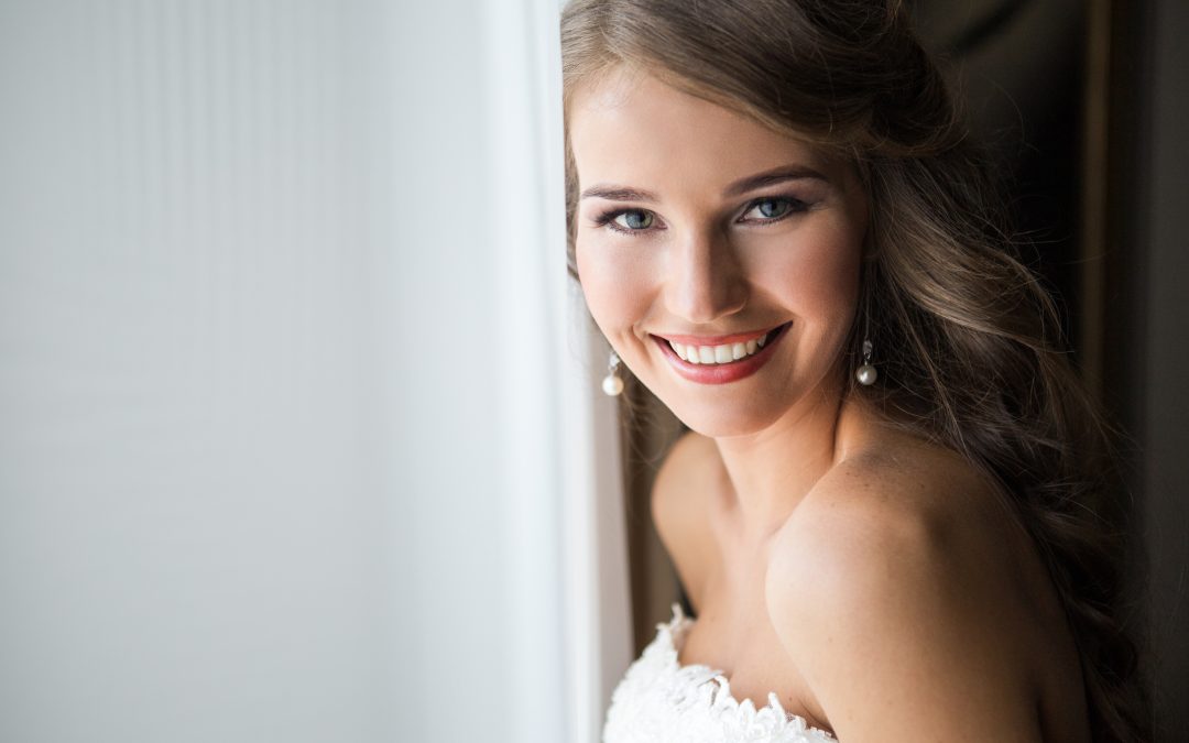 Blushing Bride In A Strapless Gown Leans Against A Door Frame